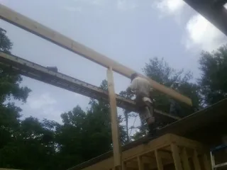 Carpenter setting a ridge beam over a new addition frame — Ice Dam Removal by Roofing Brothers in State Farm