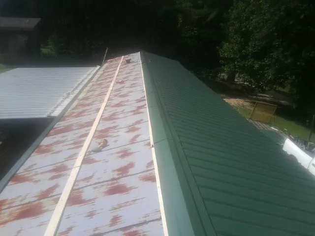 Old rusted panels beside newly installed green metal roofing — Wind Damage Roof Repair by Roofing Brothers in State Farm