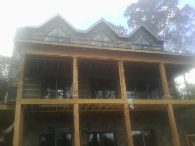 Dormers and porch framing on a large log home under construction — Roof Coating work by our crew in State Farm