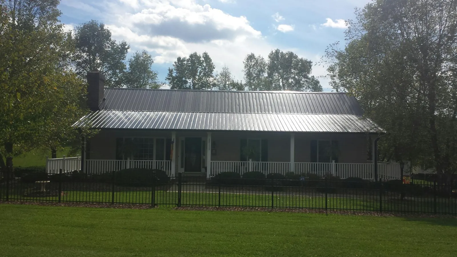 Gray metal roof on a brick ranch with a full width front porch — Gutter Guard Installation work by our crew in State Farm