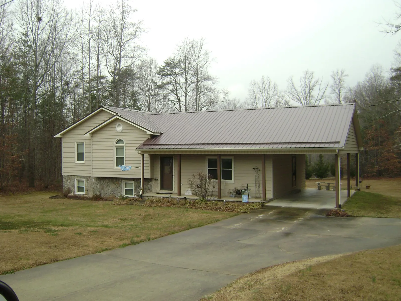 Brown metal roof on a tan split level home with an attached carport in State Farm
