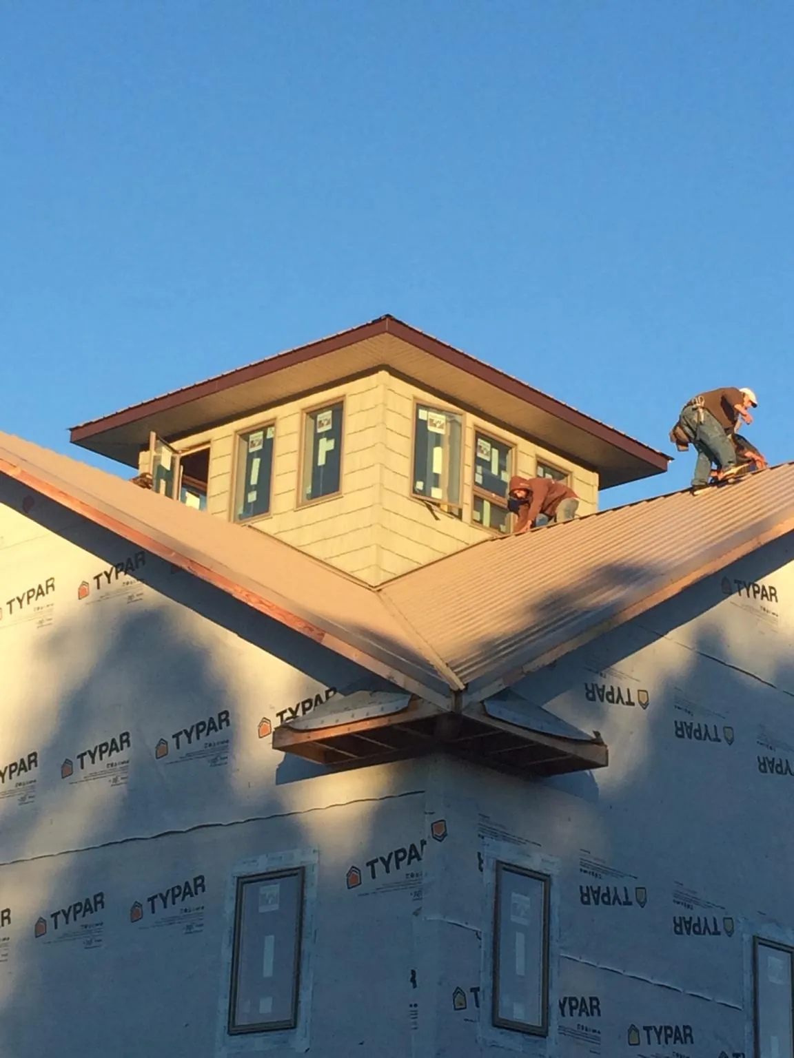 Roofers working around a rooftop cupola on a new metal roof at sunset — Roof Waterproofing in State Farm by Roofing Brothers